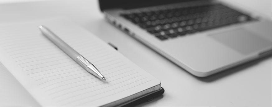 Photo of laptop and notepad on desk